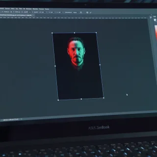 black lenovo laptop computer turned on displaying man in red shirt